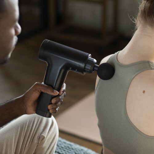 man using massage gun woman high angle(1)